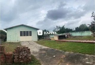 Fachada externa de uma edificação com revestimento verde claro e acesso por uma estrada de terra.