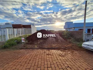 Vista externa da propriedade mostrando uma área de terra e edifícios ao fundo.