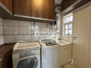 Interior da cozinha com armários de madeira e eletrodomésticos brancos.
