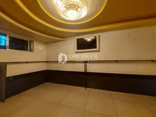 Interior de uma sala com teto decorado e revestimento de azulejos brancos.