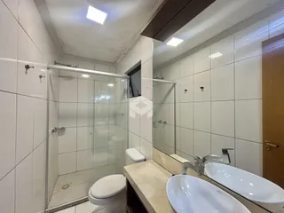 Interior de um banheiro com box de vidro e pias duplas.