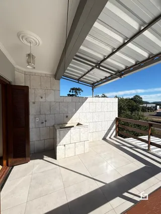 Vista de uma área externa com piso de cerâmica e grade de proteção.