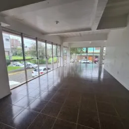 Vista de um corredor interno com grandes janelas que dão para a área externa.