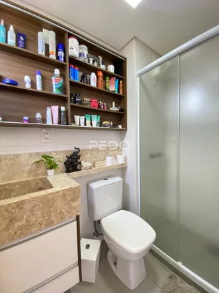 Foto de um banheiro com prateleiras de madeira e vaso sanitário branco.