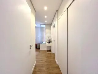 Corredor interno de uma residência com piso de madeira.