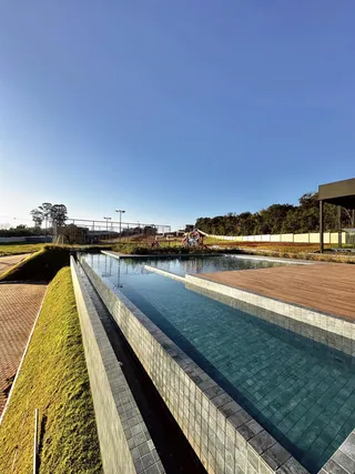 Vista de uma piscina com deck de madeira e gramado em uma área externa.