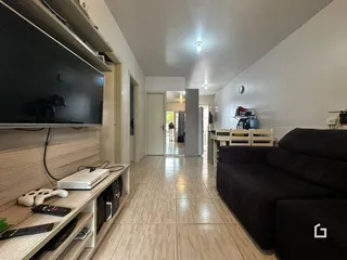 Hall de entrada com piso de madeira e parede branca em uma residência.