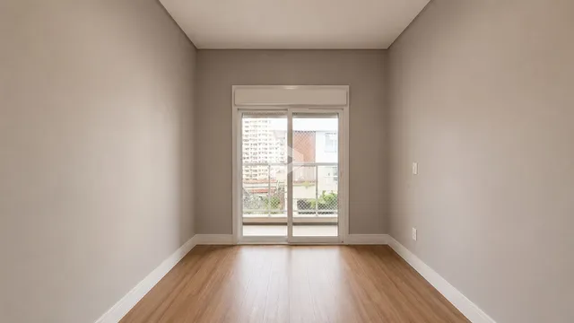 Vista interna de um ambiente com piso de madeira clara e paredes neutras.