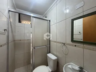 Foto de um banheiro com revestimento cerâmico e box de vidro.