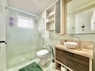 Foto de um banheiro com box de vidro e revestimento cerâmico.