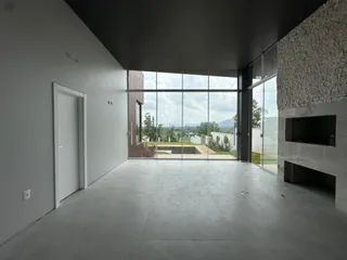 Sala ampla com grande abertura de vidro e vista para a paisagem externa.
