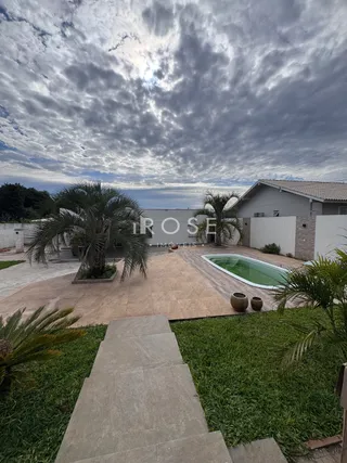 Vista externa de uma propriedade com piscina e jardim.