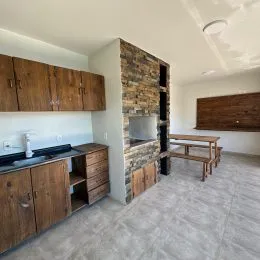 Interior de uma cozinha com armários de madeira e parede de tijolos aparentes.