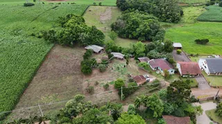 Vista aérea de uma propriedade rural com campos e vegetação ao redor.