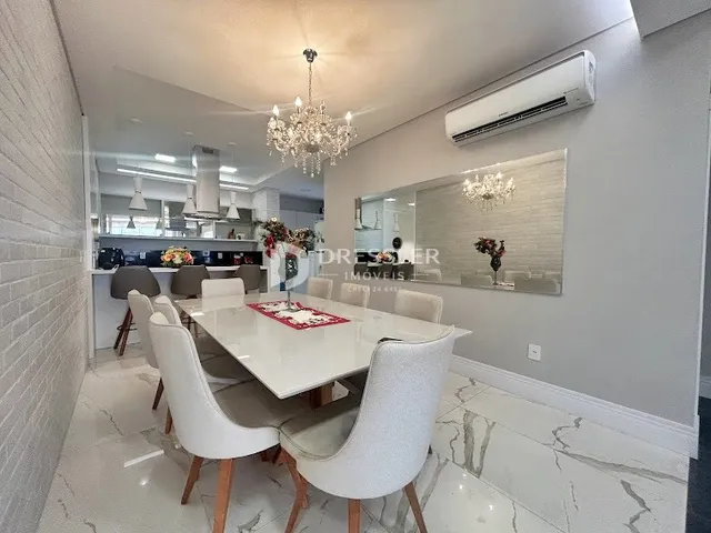 Uma sala de jantar moderna com mesa e cadeiras brancas.