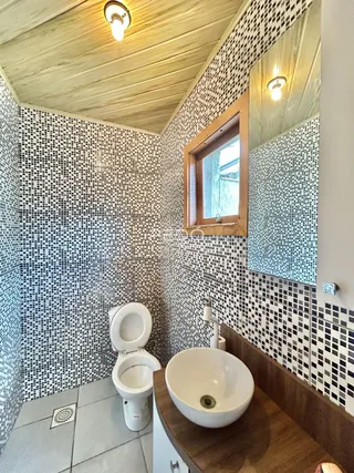 A foto mostra um banheiro com revestimento de azulejos pretos e brancos.