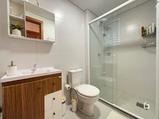 Foto de um banheiro moderno com box de vidro e louças brancas.