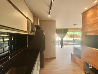 Vista da cozinha com piso de madeira e parede de tijolos expostos.