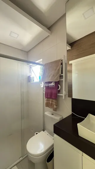 Banheiro com revestimento cerâmico e box de vidro.