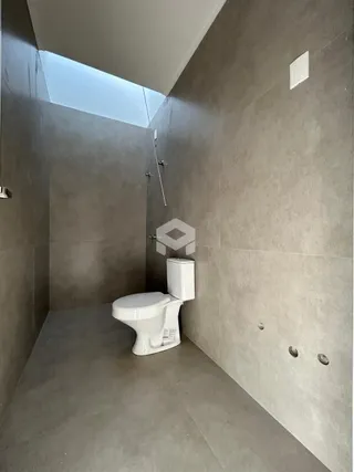 Corredor com vaso sanitário branco em ambiente de concreto.