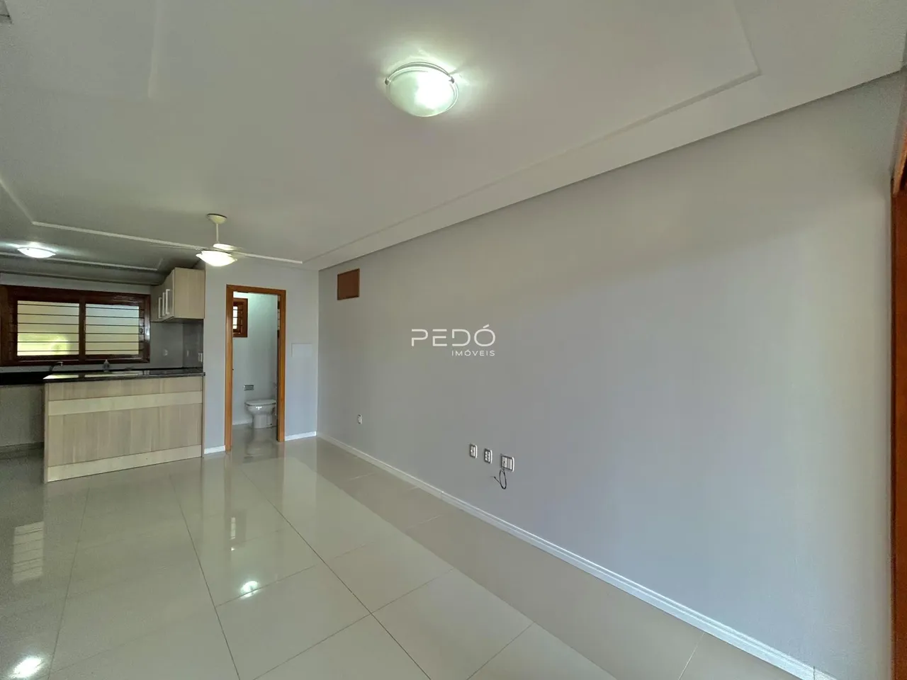 Ambiente interno de uma sala com piso de cerâmica e paredes brancas.
