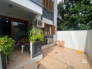 Vista externa da casa com área de piso de terracota e jardim.