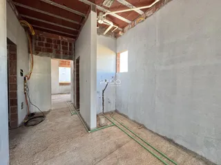 Corredor interno de uma residência com paredes de alvenaria expostas.