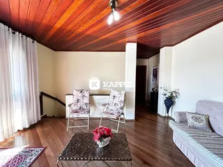 Sala de estar com piso de madeira e cortinas brancas.