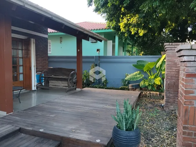 Fachada de uma residência com deck de madeira e vegetação no quintal.