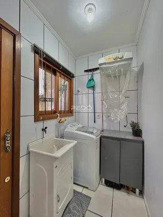 Foto de um ambiente interno com revestimento cerâmico branco e janela de madeira.