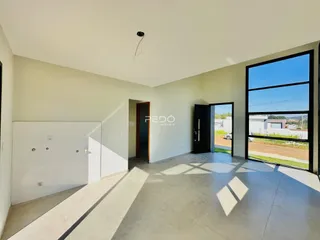 Ambiente interno de uma sala ampla com piso de cerâmica e grande janela.