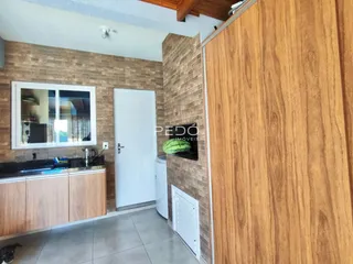 A cozinha com armários de madeira e piso cerâmico é visível na imagem.