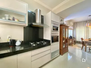 Cozinha moderna com armários brancos e bancada escura.
