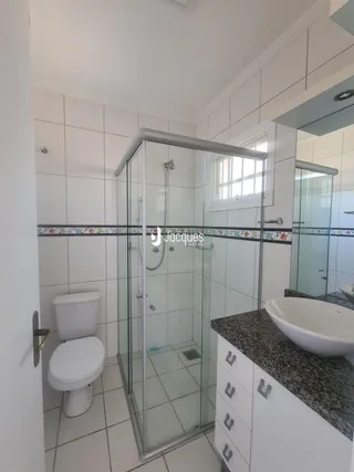 Banheiro com box de vidro e revestimento cerâmico.