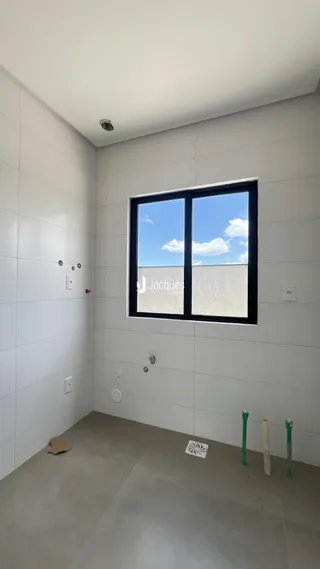 Foto de um ambiente interno com paredes brancas e uma grande janela.