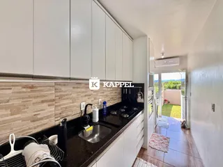 Cozinha moderna com armários brancos e bancada escura.