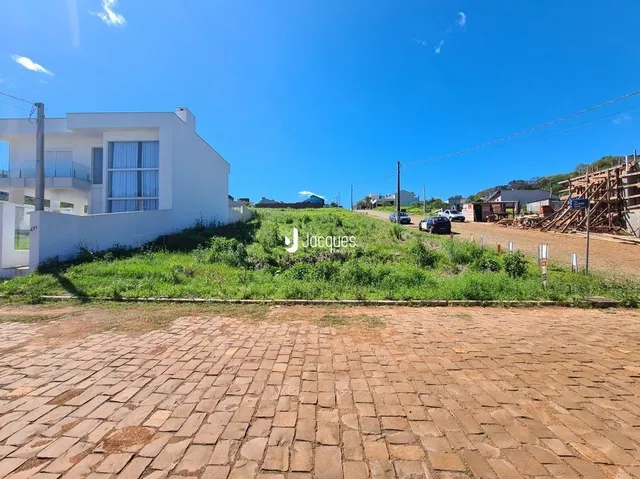 Fachada de uma casa branca em Lajeado, Brasil, com jardim e pátio de tijolos.