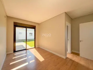 Interior de uma sala com piso de madeira e porta de vidro que dá para o exterior.