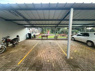 Área externa pavimentada sob uma estrutura de telhado.