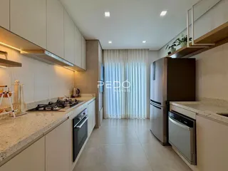 Cozinha moderna com armários brancos e piso claro em imóvel no Brasil.