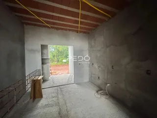 Espaço interno com paredes de concreto aparente e piso de cimento.