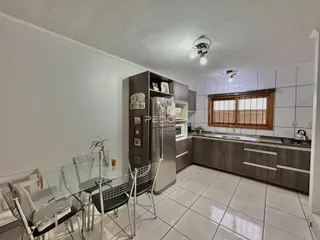 Imagem de uma cozinha com armários e área de jantar em um imóvel no Brasil.