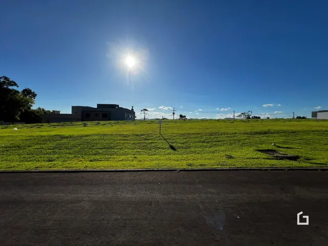 Vista externa de uma propriedade com gramado verde e um edifício ao fundo.