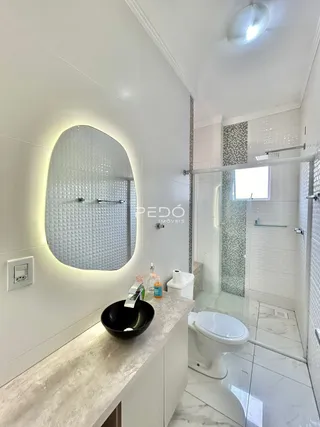 Interior de um banheiro moderno com revestimentos brancos e detalhes em mosaico.