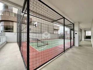 Vista externa de uma área de lazer com quadra esportiva cercada por tela.
