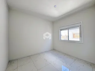 Ambiente interno de uma sala com piso de porcelanato branco e janela.