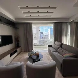 Sala de estar com sofá e janela ampla em um apartamento.