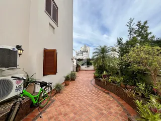 Vista da fachada de uma residência com jardim e calçada de tijolos.