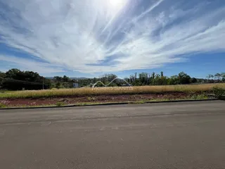 Vista de uma paisagem rural com campo seco e montanhas ao fundo.