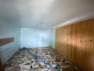 Quarto com piso estampado e parede de madeira no interior da propriedade.